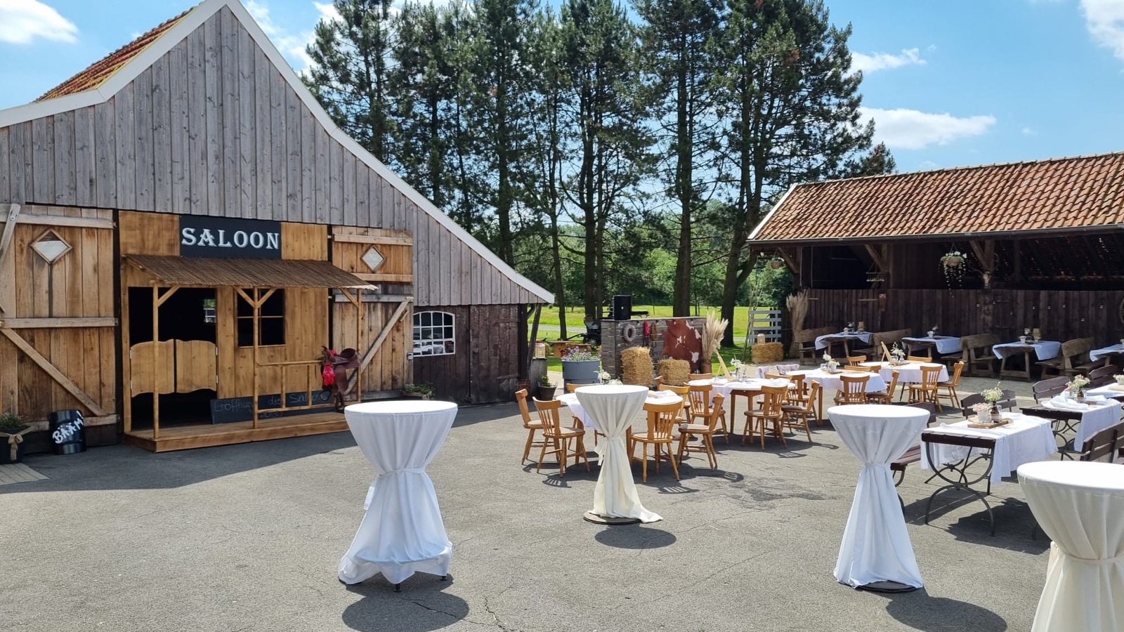 Saloon-Fassade der Festscheune mit Stehtischen auf dem Eichenhof