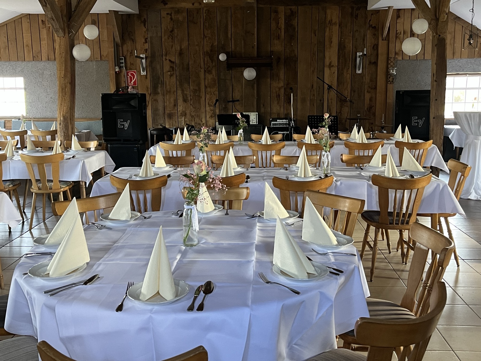 Festlich gedeckte runde Tische in der Sommerscheune
